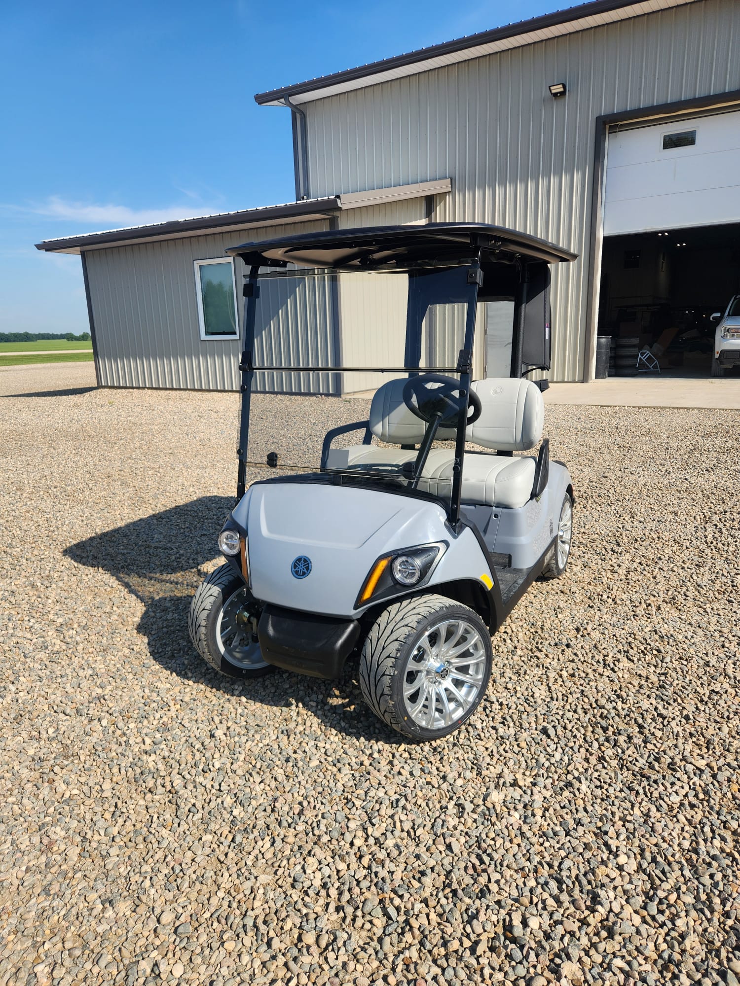 White Yamaha cart with chrome wheels on gravel