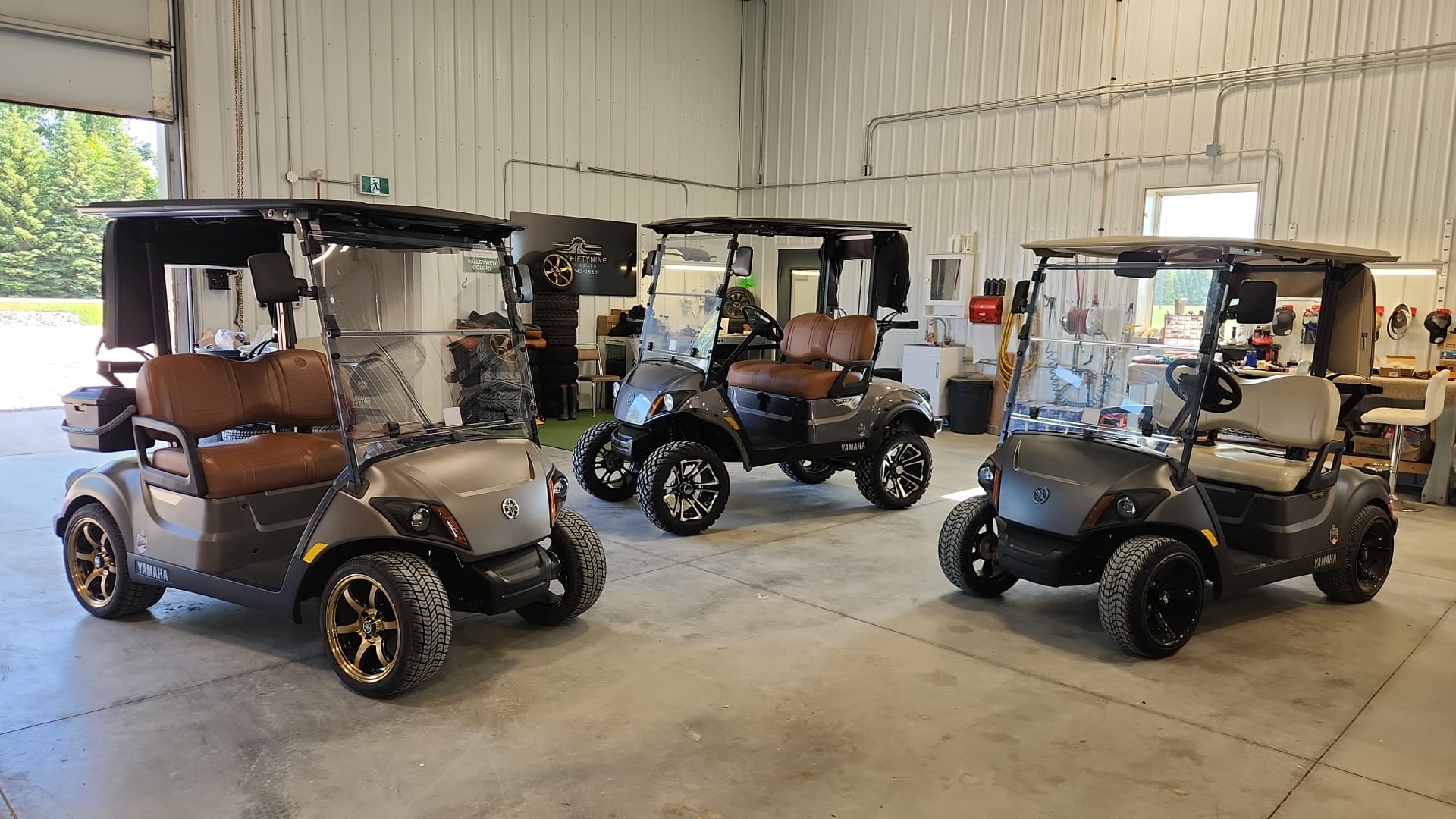 Three custom Yamaha carts lined up inside the Road Fiftynine shop