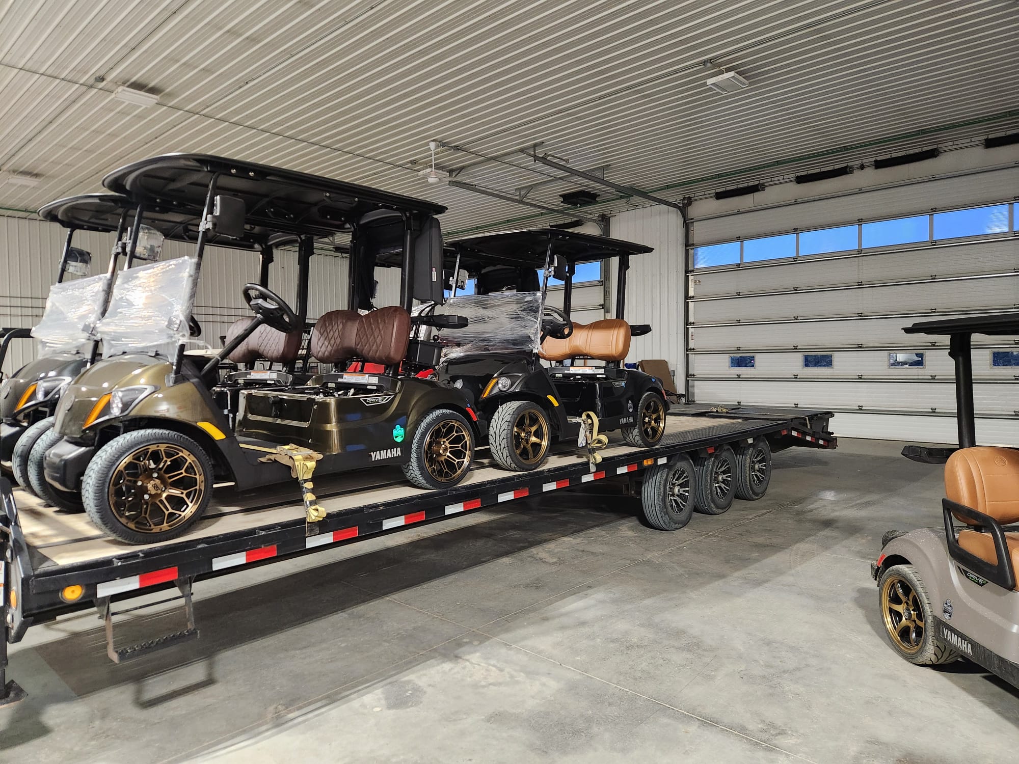 Custom Yamaha carts loaded on a trailer inside the shop, ready for delivery
