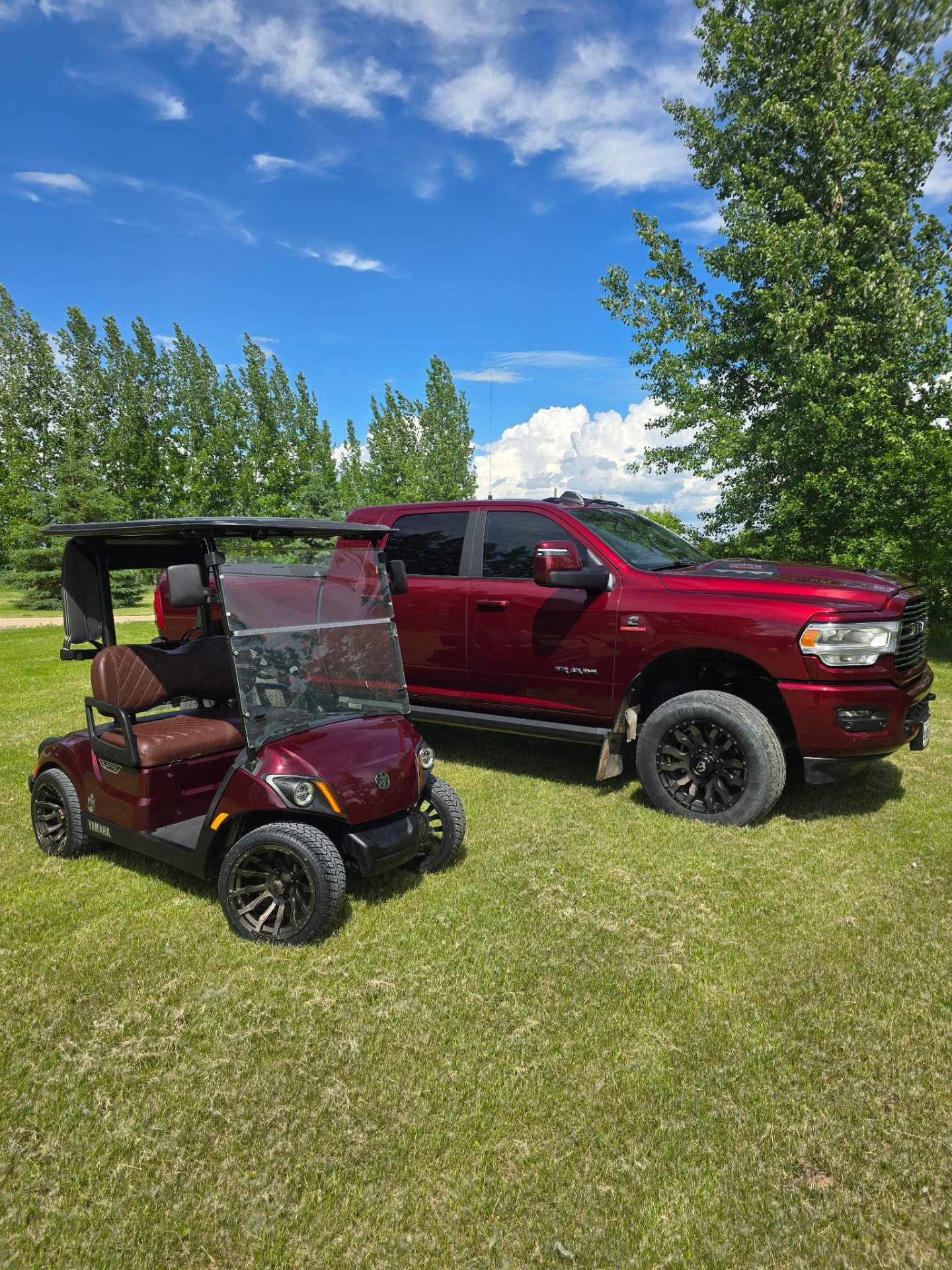 Maroon Yamaha cart beside a matching red Ram truck